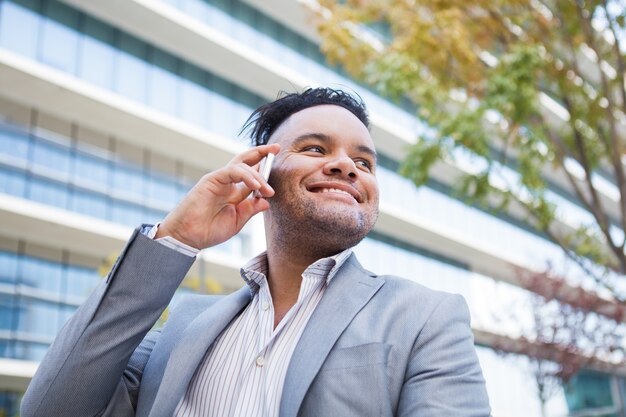 Administrador joven satisfecho disfrutando de la conversación telefónica