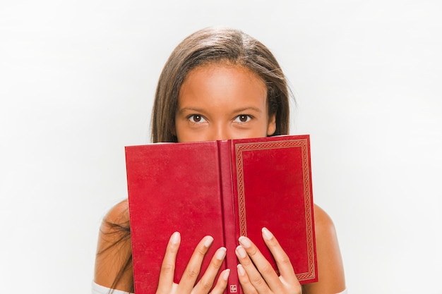 Foto gratuita adolescente africano cubriendo su rostro detrás del cuaderno