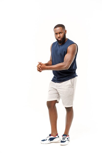 Adolescente afroamericano muestra los músculos del brazo. Aislado sobre fondo blanco. Retrato de estudio. Concepto de edad de transición