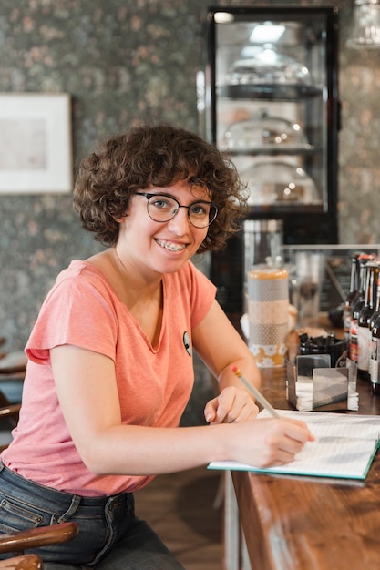 Adolescente alegre haciendo la tarea en el café