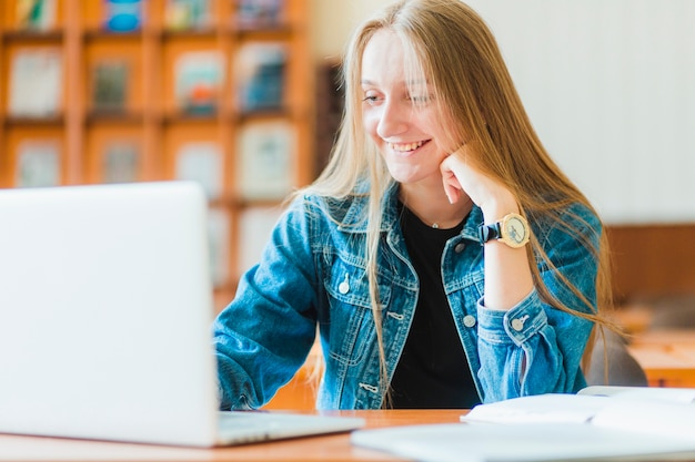 Foto gratuita adolescente alegre que usa la computadora portátil durante la lección