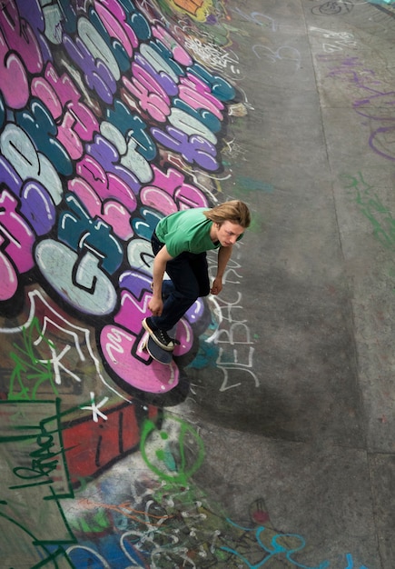 Adolescente de alto ángulo haciendo trucos en patineta