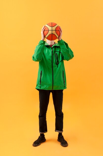 Adolescente de alto ángulo jugando con pelota de baloncesto