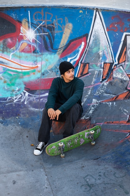 Foto gratuita adolescente de alto ángulo sentado en skatepark