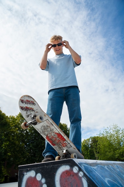 Foto gratuita adolescente de ángulo bajo con gafas de sol