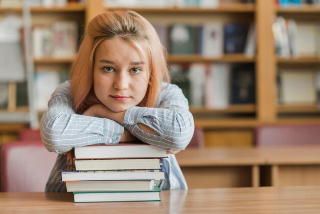 Adolescente apoyado en la pila de libros