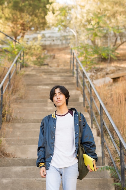 Foto gratuita adolescente asiático caminando por las escaleras con el libro en la mano