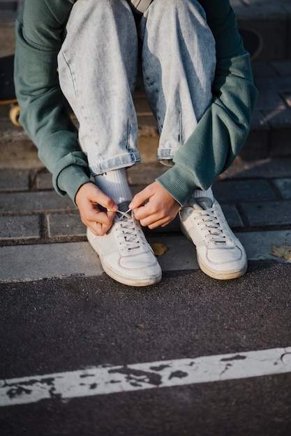 Adolescente atar los cordones de los zapatos al aire libre