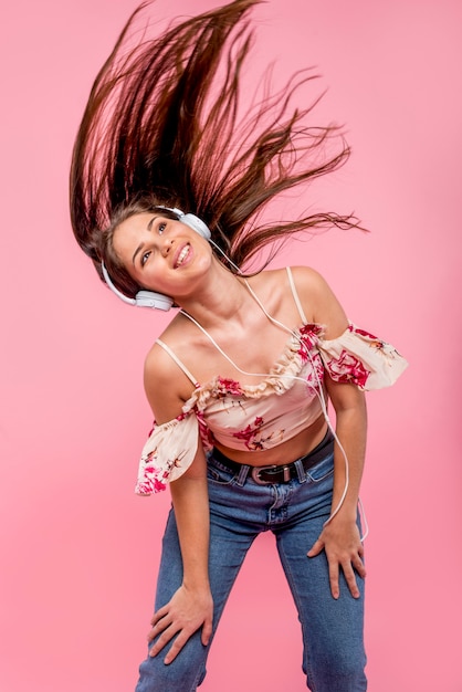 Adolescente en auriculares escuchando música y agitando el cabello