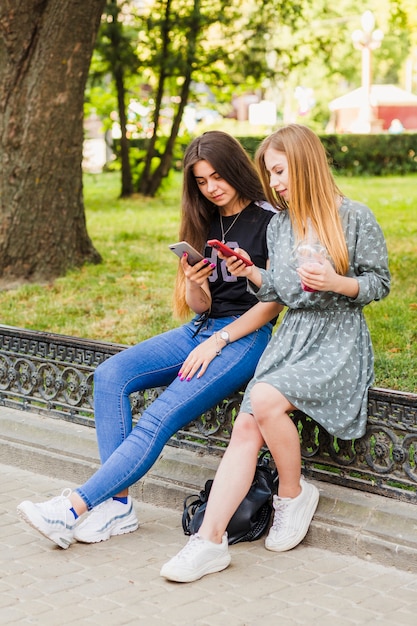 Adolescente con bebida usando teléfonos inteligentes