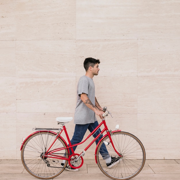 Adolescente caminando con su bicicleta cerca de la pared