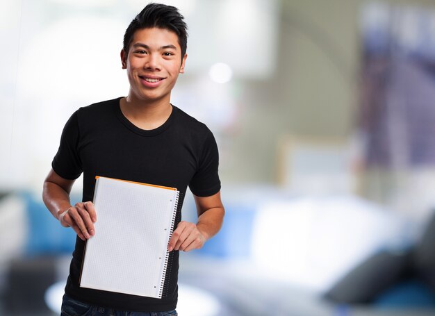 Adolescente con camiseta negra mostrando un cuaderno en blanco