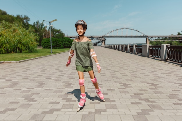 Adolescente en un casco aprende a andar en patines al aire libre