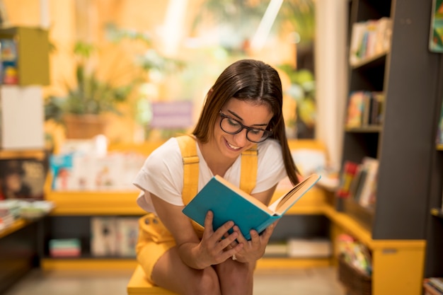 Adolescente colegiala leyendo libro cautivado