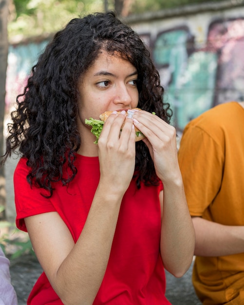 Adolescente comiendo una hamburguesa al aire libre