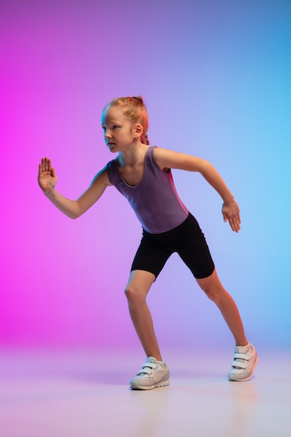 Adolescente corriendo, trotando contra el estudio de neón rosa-azul degradado en movimiento