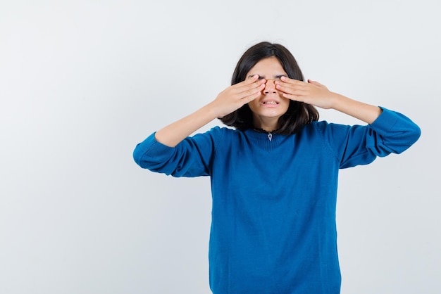 La adolescente se cubre los ojos con las manos en el fondo blanco