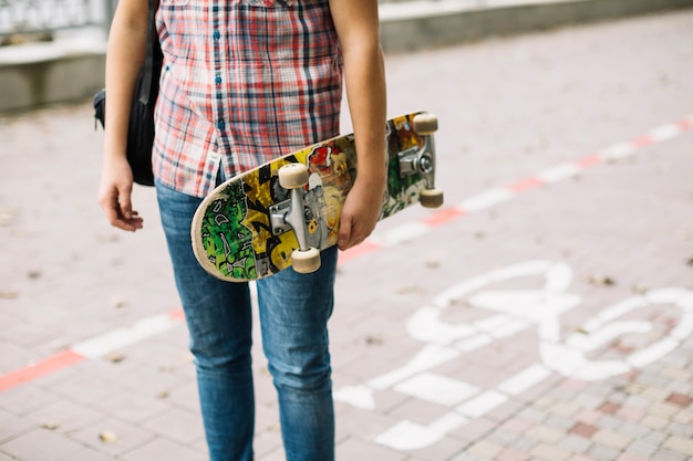 Foto gratuita adolescente de cultivos con patineta colorida