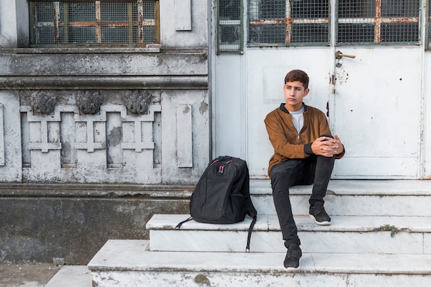 Foto gratuita adolescente elegante serio que se sienta en escalera