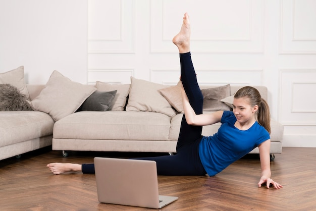 Adolescente entrenando en casa mientras mira instrucciones