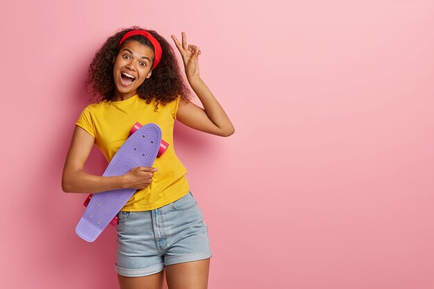 Adolescente entusiasta con el pelo rizado posando en camiseta amarilla