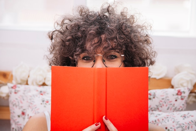 Foto gratuita adolescente escondiendo la cara detrás del libro