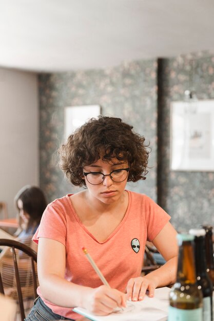 Adolescente escribiendo en el cuaderno en el café