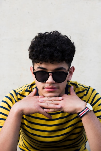 Adolescente étnico en camisa brillante a rayas y gafas de sol.