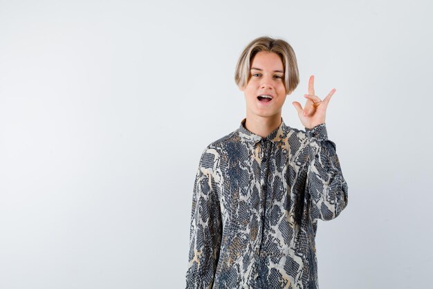 El adolescente feliz apunta hacia arriba con la mano en el fondo blanco