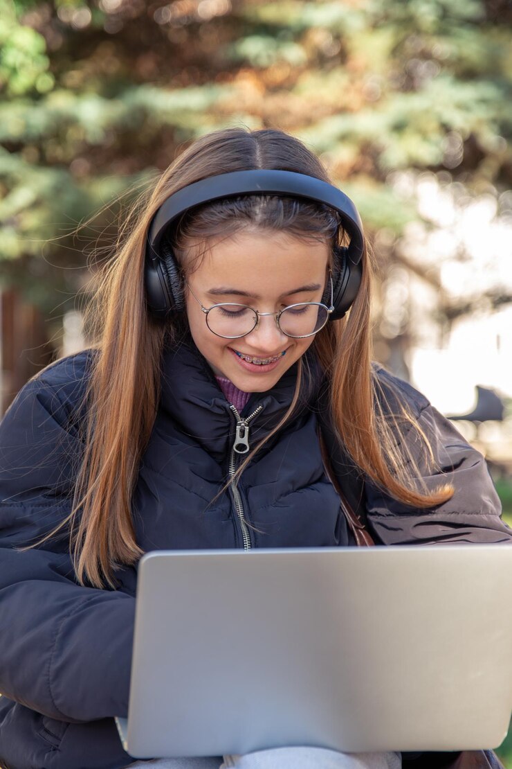 Foto gratuito una adolescente feliz con auriculares trabaja en un concepto de emociones de portátil