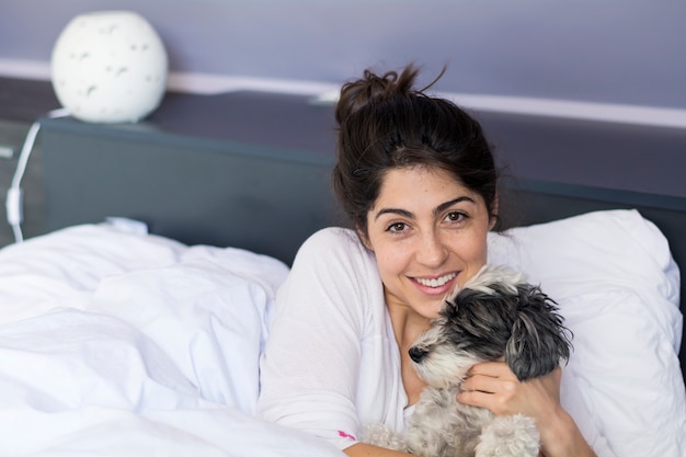 Foto gratuita adolescente feliz posando con su perro en el dormitorio