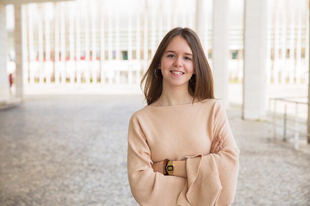 Adolescente femenino sonriente que presenta en la cámara al aire libre