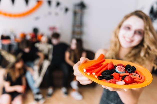 Adolescente en la fiesta de Halloween dando plato con mermelada