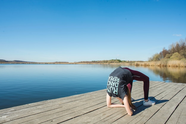 Foto gratuita adolescente flexible haciendo yoga en el muelle