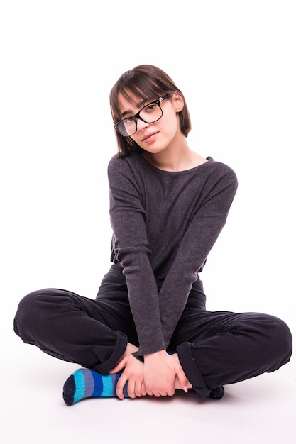 Adolescente con gafas sentado en el suelo aislado