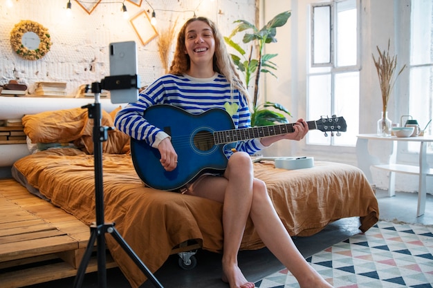 Adolescente grabando música en casa estudio con guitarra