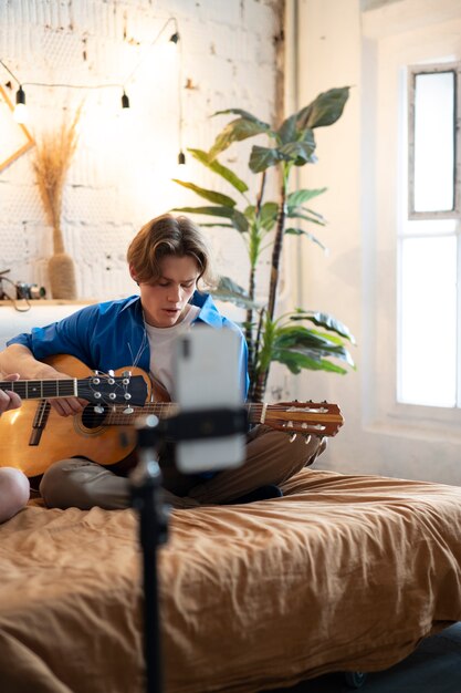 Adolescente grabando música con su guitarra en el estudio de su casa