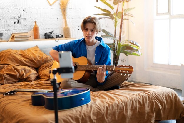 Adolescente grabando música con su guitarra en el estudio de su casa