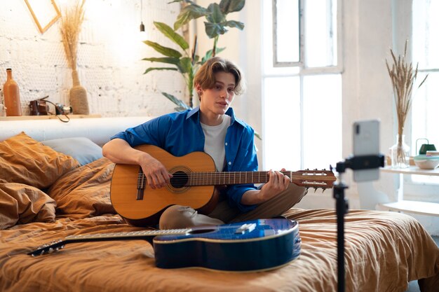 Adolescente grabando música con su guitarra en el estudio de su casa