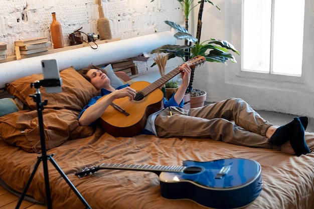 Adolescente grabando música con su guitarra en el estudio de su casa