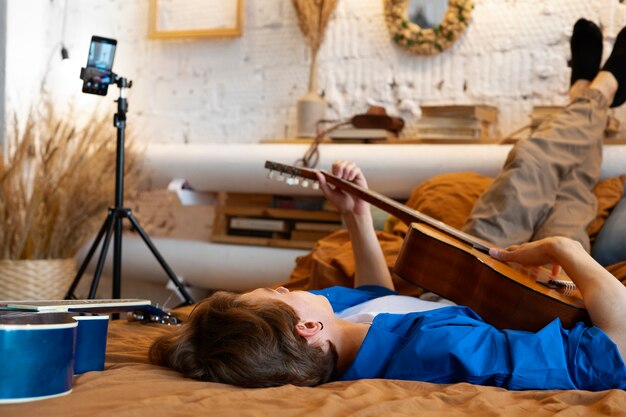 Adolescente grabando música con su guitarra en el estudio de su casa