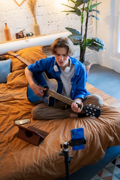 Adolescente grabando música con su guitarra en el estudio de su casa