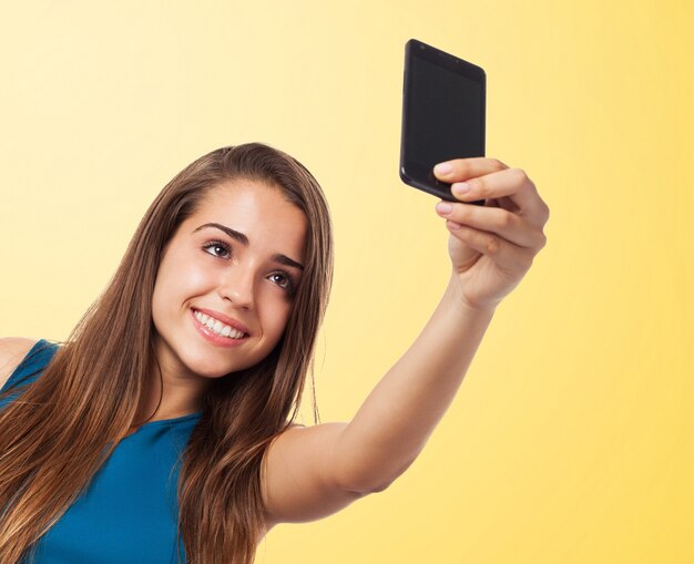 Adolescente guapa haciéndose una foto con fondo naranja