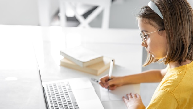 Una adolescente hace su tarea mientras está sentada con libros y una computadora portátil