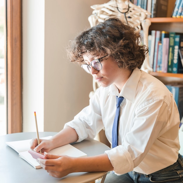 Adolescente haciendo tareas de matemáticas en la biblioteca