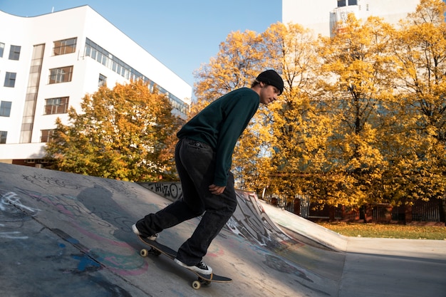 Foto gratuita adolescente haciendo trucos en monopatín al aire libre tiro completo