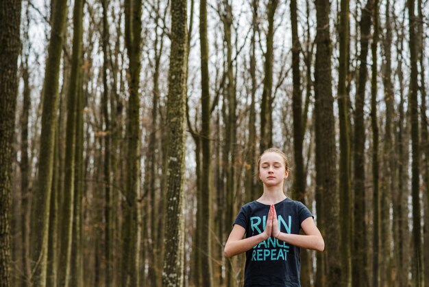 Adolescente haciendo yoga y relajante en el bosque