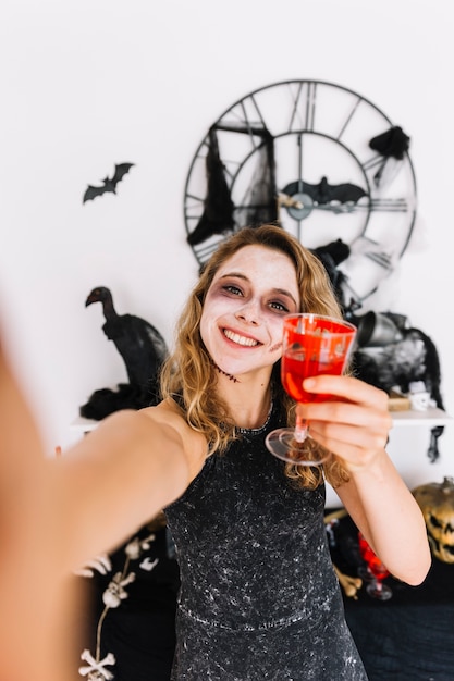 Adolescente de Halloween con vidrio rojo con sangre falsa