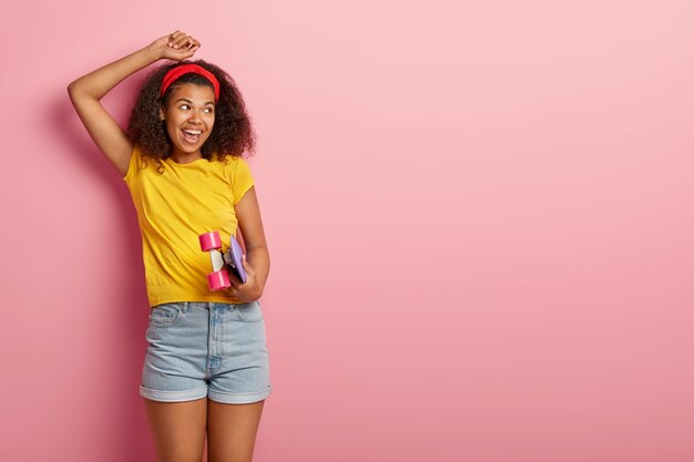 Adolescente hipster con pelo rizado posando en camiseta amarilla