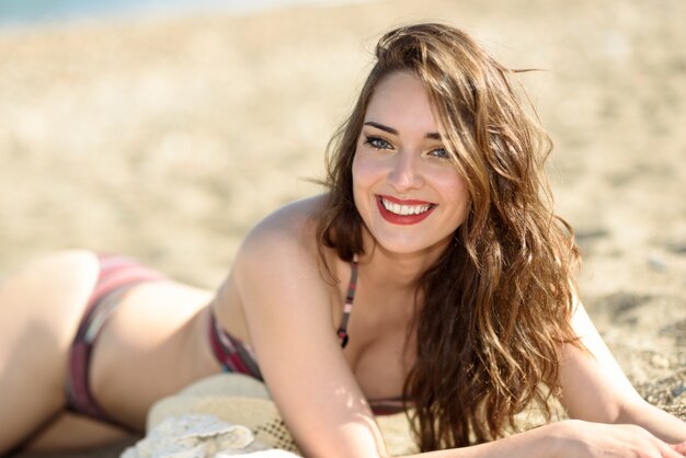 Adolescente con los labios rojos tomando el sol en la playa